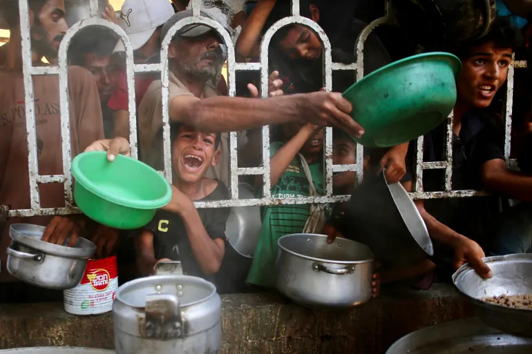 Palestinians gather to receive a meal at a charity kitchen in the al-Mawasi area of Khan Younis in southern Gaza [AFP]