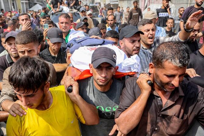 Mourners carry Al Jazeera journalists killed in overnight Israeli strike from Al-Shifa Hospital to burial in Gaza City. (AFP)