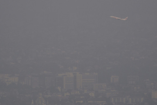 An airplane flies over a busy road as it lands at Chiang Mai International Airport amid high levels of air pollution in Chiang Mai on March 15, 2024. (AFP)