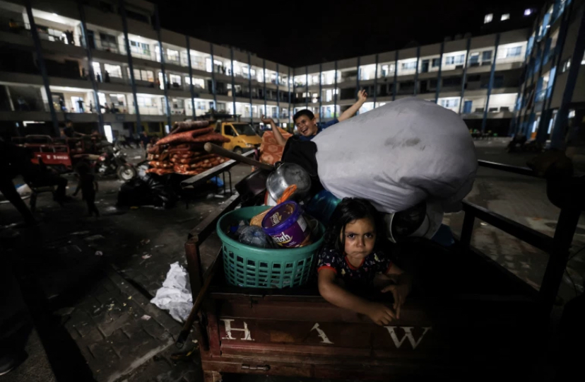 A family that was sheltering at a United Nations run school, return with their belongings to their home following the ceasefire [Mohammed Abed/AFP]