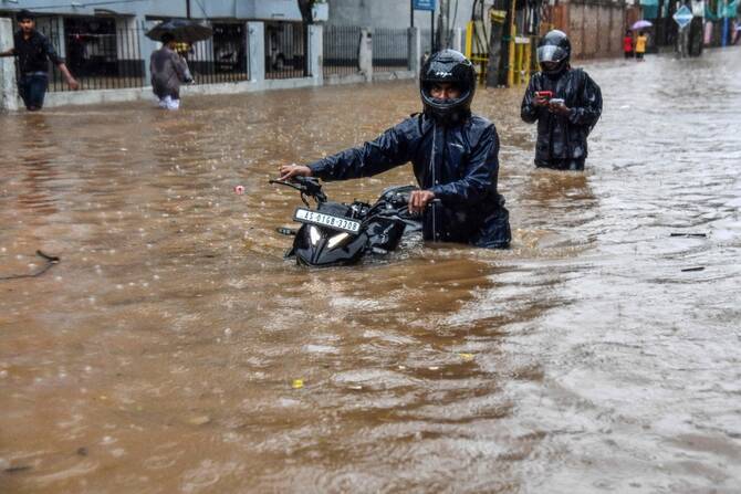 Residents walk through a flooded street after heavy rainfalls in Guwahati, India. (AFP)