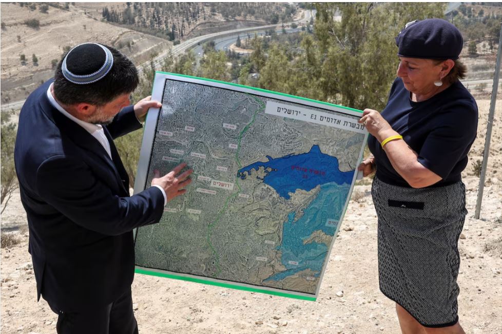 Israeli Finance Minister Bezalel Smotrich and a woman hold a map that shows the long-frozen E1 settlement scheme. REUTERS/Ronen Zvulun