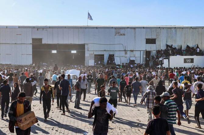 Displaced Palestinians ferry bags of food aid after storming a World Food Programme warehouse in Deir Al-Balah in the central Gaza Strip on Wednesday. (AFP)