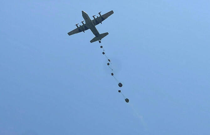 Aid packages dropped from an airplane descend over Gaza, as seen from the central Gaza Strip, on Saturday. (Reuters)