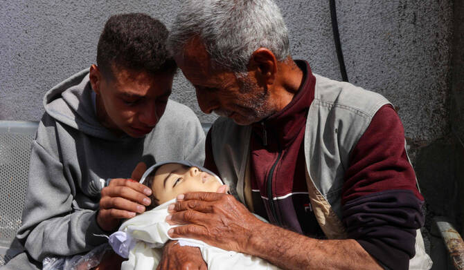 Palestinians mourn over the shrouded body of a child, killed during an Israeli strike earlier on Al-Jalaa street, at Al-Shifa hospital in the central Gaza Strip on April 28, 2025. (AFP)