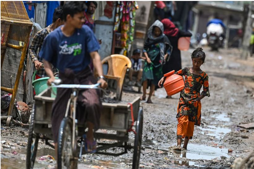 A Rohingya girl walks through a muddy street at a refugee camp in New Delhi in June. Photo: AFP