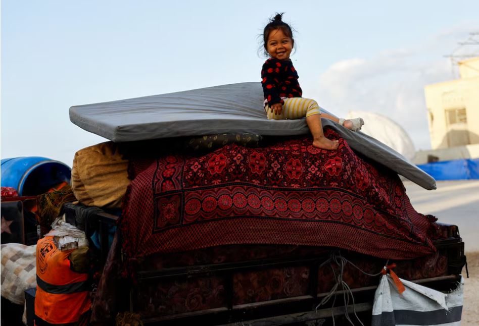 A child sits atop belongings as displaced Palestinians return north following Israel’s ceasefire with Hamas, in central Gaza, October 10, 2025. REUTERS/Mahmoud Issa