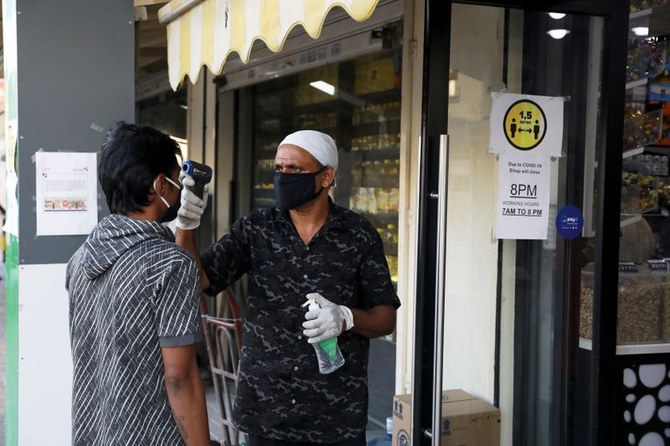 A man has his temperature taken outside a corner store in Dubai. Photo Reuters.