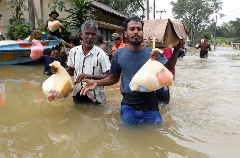 Sri Lankan flood victims carry dry rations at a flood-affected area after heavy rainfall in a suburb of Colombo, Sri Lanka. Photograph: Chamila Karunarathne/EPA