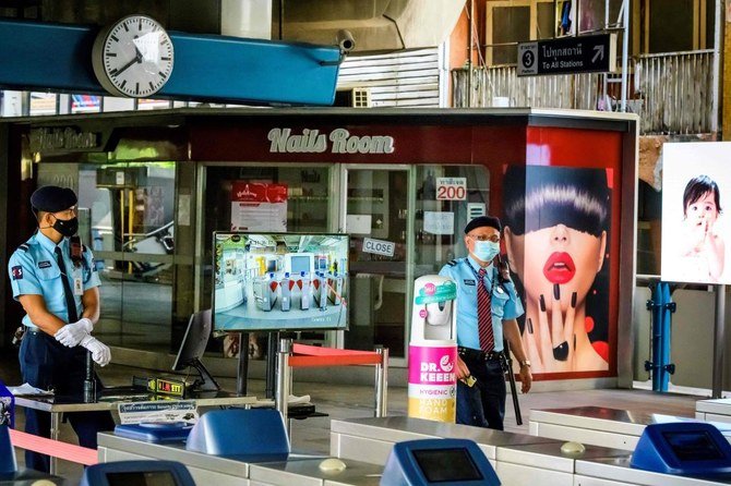 Bangkok Security officials stand next to a temperature control point in front of a closed nail salon. Photo: AFP