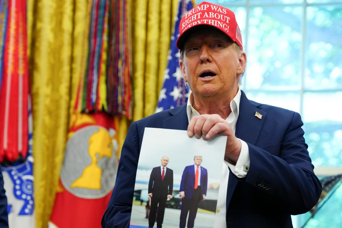 US President Donald Trump holding a photo of himself with Russian President Putin in Alaska, while speaking in the Oval Office on Aug 22.  PHOTO: TIERNEY L. CROSS/NYTIMES
